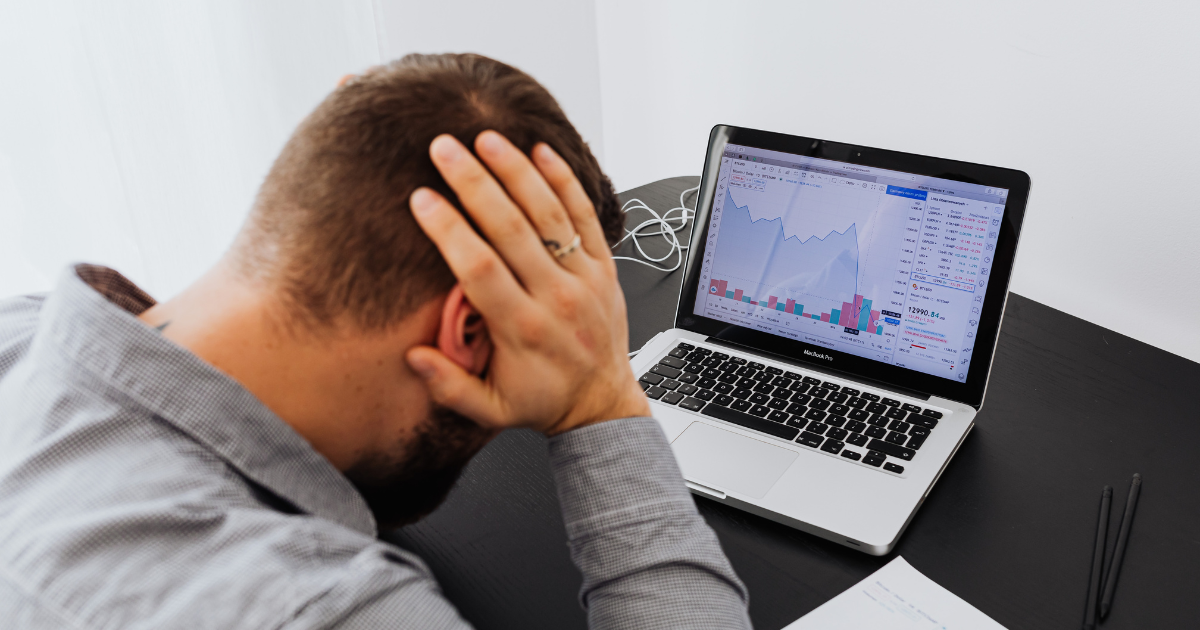 株のモニターの前で頭を抱える男性